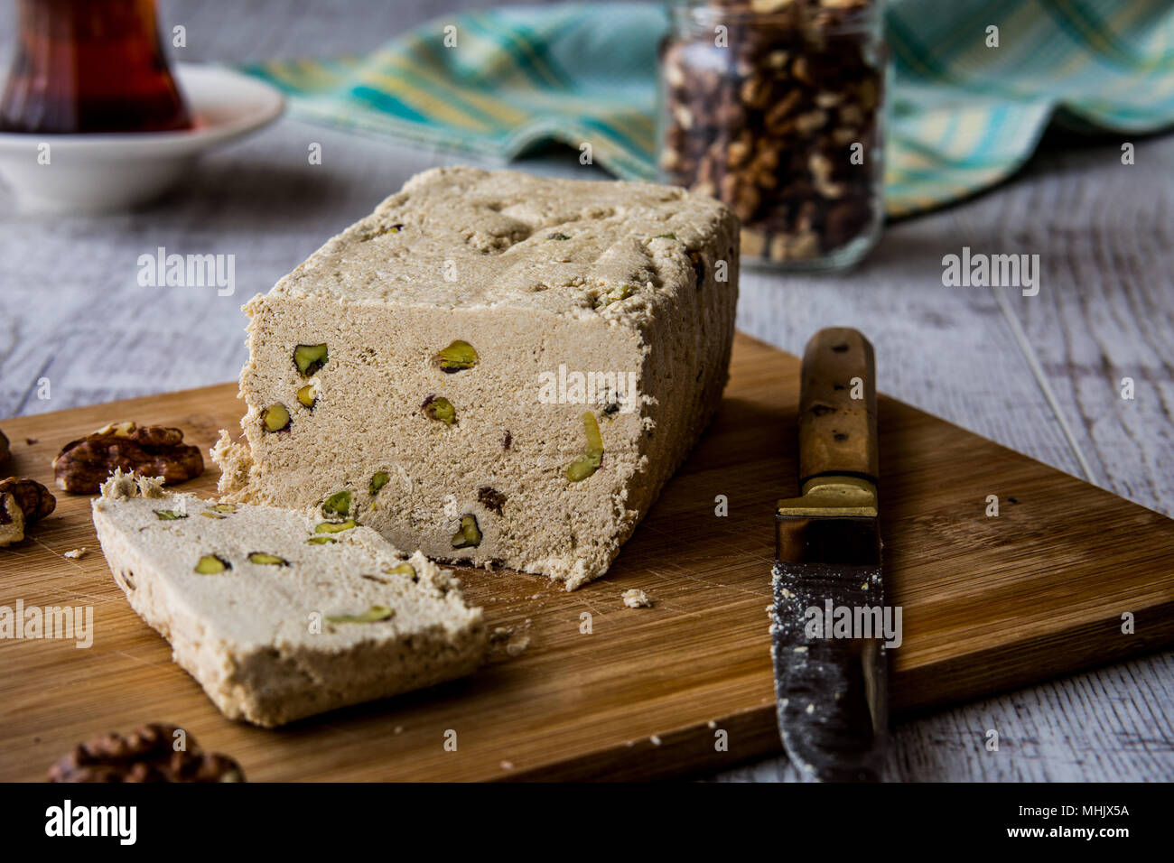 Slices of Halva / Helva with peanut walnut and tea on a wooden surface ...