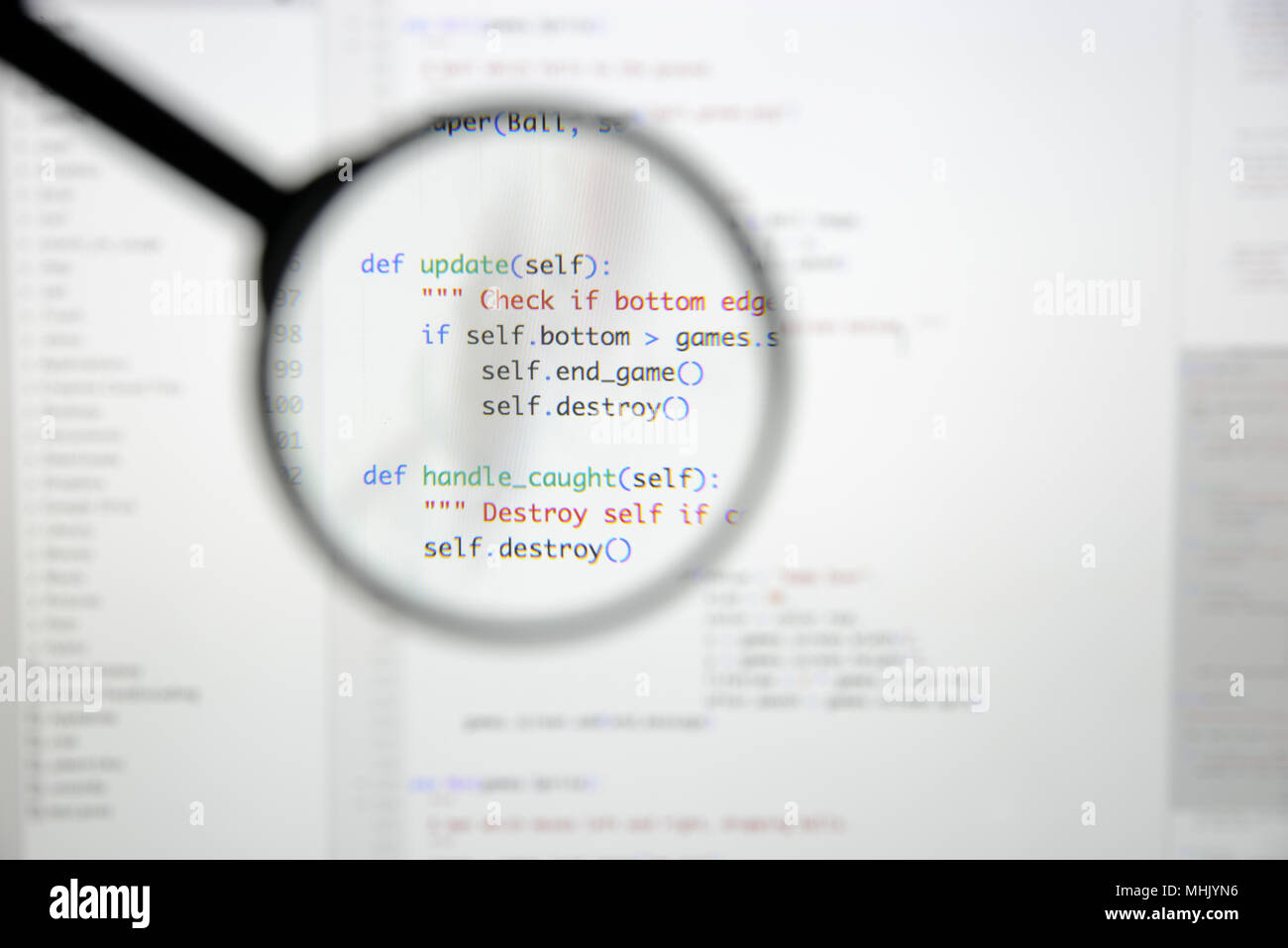 Real Python code developing screen. Programing workflow abstract algorithm concept. Lines of Python code visible under magnifying lens. Stock Photo