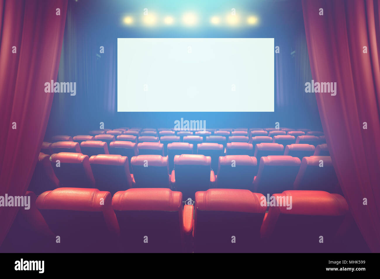 empty theater auditorium with blank screen or movie cinema with red seats before show time Stock Photo