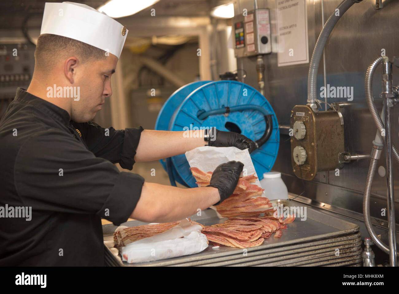 MEDITERRANEAN SEA (March 25, 2018) Marine Corps Staff Sgt. Salvatore Dely, from Tucson, Az., assigned to the Battalion Landing Team, 26th Marine Expeditionary Unit, places bacon on a sheet pan in preparation for brunch aboard the San Antonio-class amphibious transport dock ship USS New York (LPD 21) March 25, 2018. New York, homeported in Mayport, Fla., is conducting naval operations in the U.S. 6th Fleet area of operations. (U.S. Navy Stock Photo
