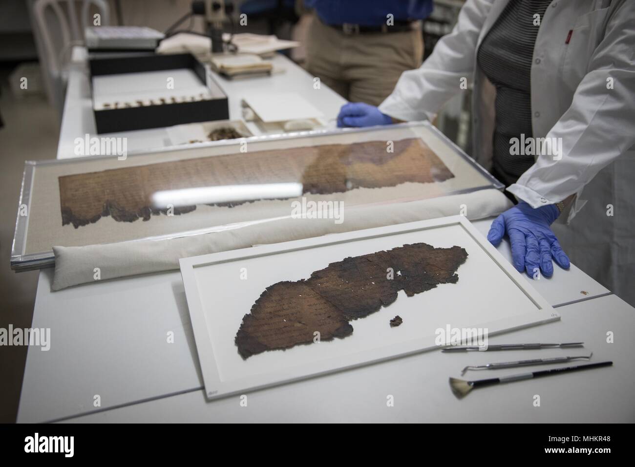 Jerusalem. 2nd May, 2018. Israel Antiquities Authority (IAA) staff members show fragments of a script at the IAA department in the Israel Museum in Jerusalem, on May 2, 2018. Advanced imaging technology originally developed for NASA has revealed previously unnoticed writing on fragments of the Dead Sea Scrolls, the IAA revealed on Tuesday. Moreover, one of the newly discerned and deciphered passages, written in early Hebrew, hints at the existence of a scroll never found and still unknown to researchers. Credit: JINI/Xinhua/Alamy Live News Stock Photo