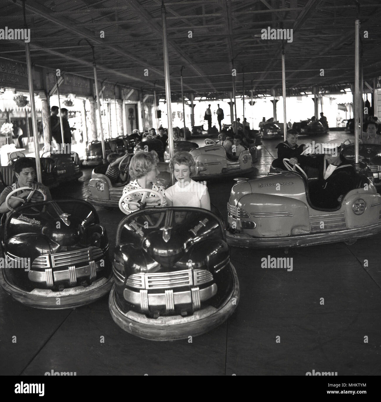 1960s, historical, two attractive young women riding together in a open  dodgem or bumper car at Battersea fun fair, Battersea Park, London,  England, UK. The fun fair was built in the park