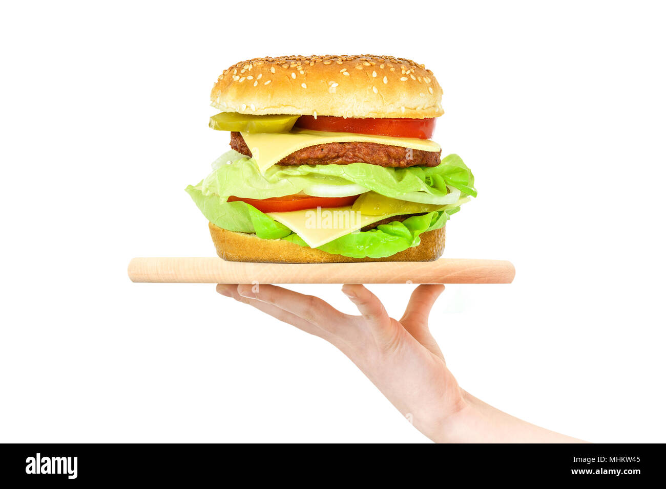 Concept of food serving service - female hand holding a wooden board with a big hamburger on a white background (mixed) Stock Photo