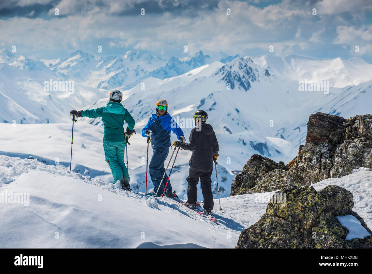 A ski instructor talks to a male and female skier at altitude in the French alpine resort of Courchevel. Stock Photo