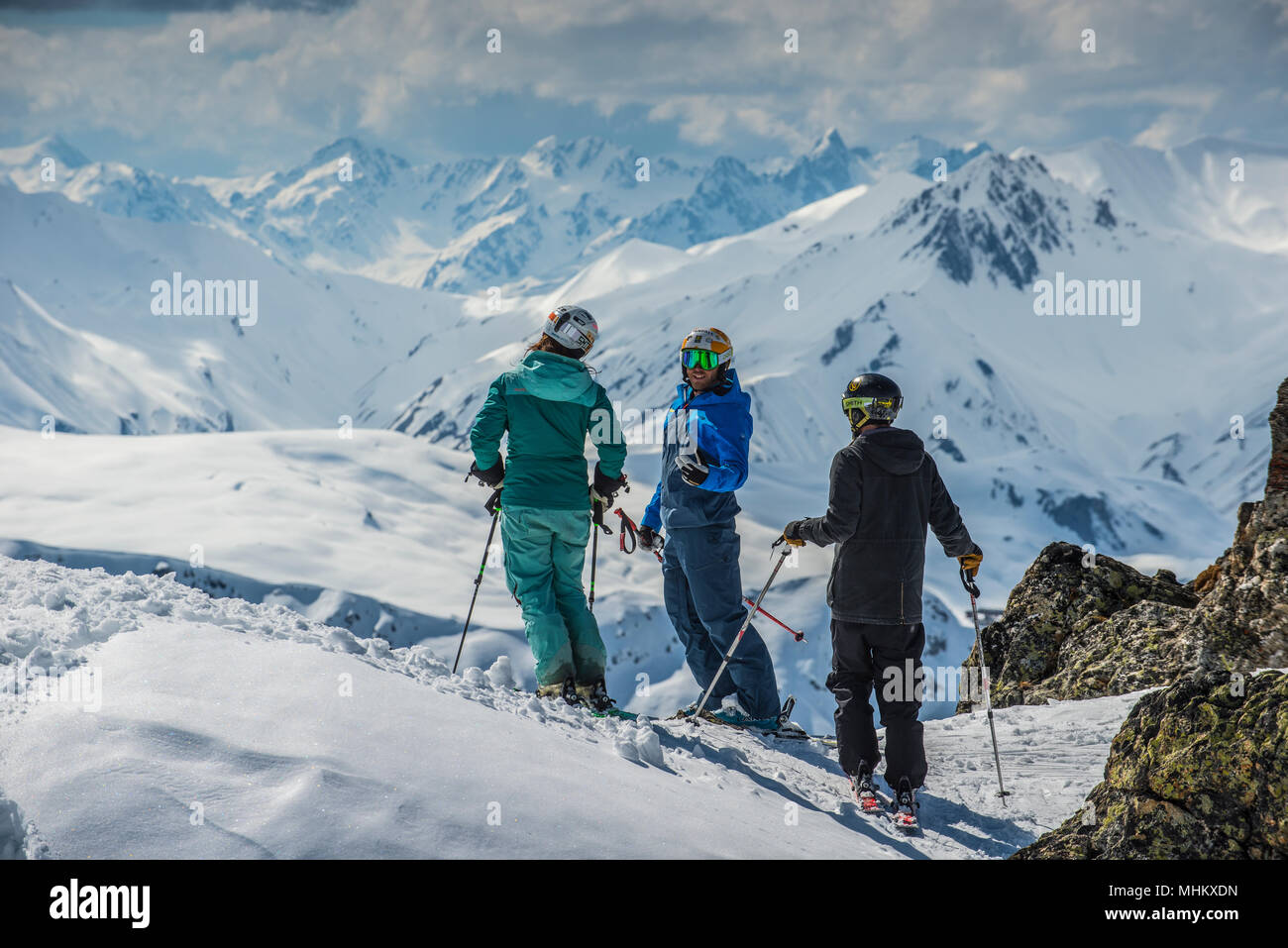 A ski instructor talks to a male and female skier at altitude in the French alpine resort of Courchevel. Stock Photo