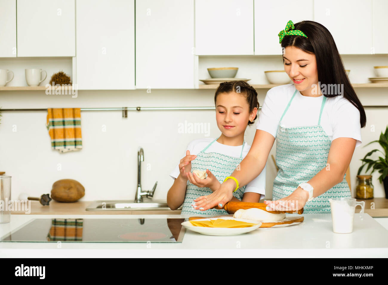 Flour and fun make for some delicious food. Shot of a pretty girl having fun baking with her mother at white kitchen Stock Photo