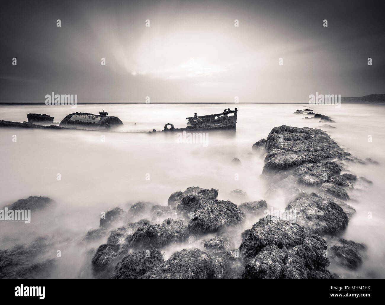 Black and white ship wreck, long exposure with sea and rocks. Stock Photo