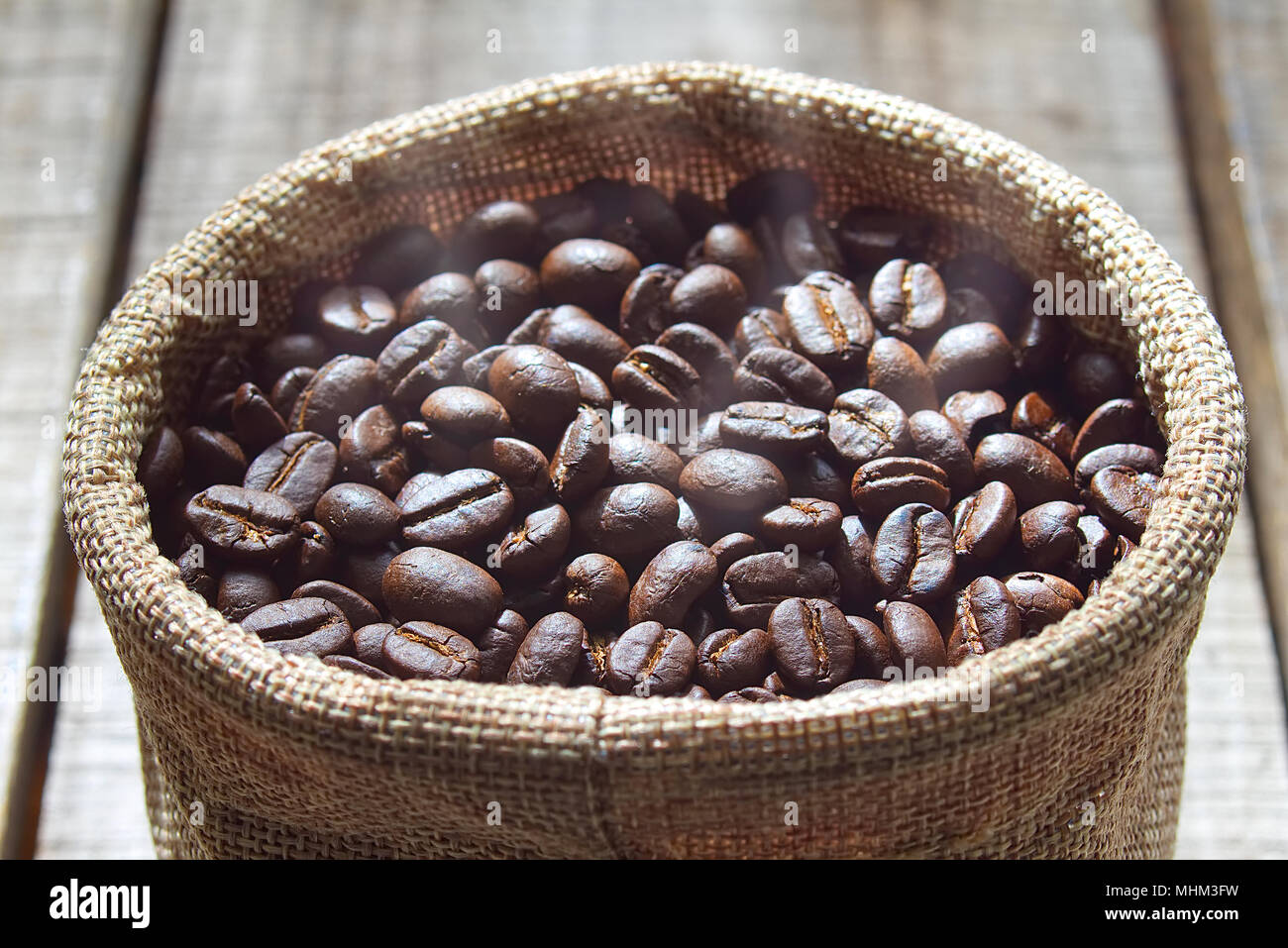 Close up fresh coffee beans keep in bag after blending on wood table. Stock Photo