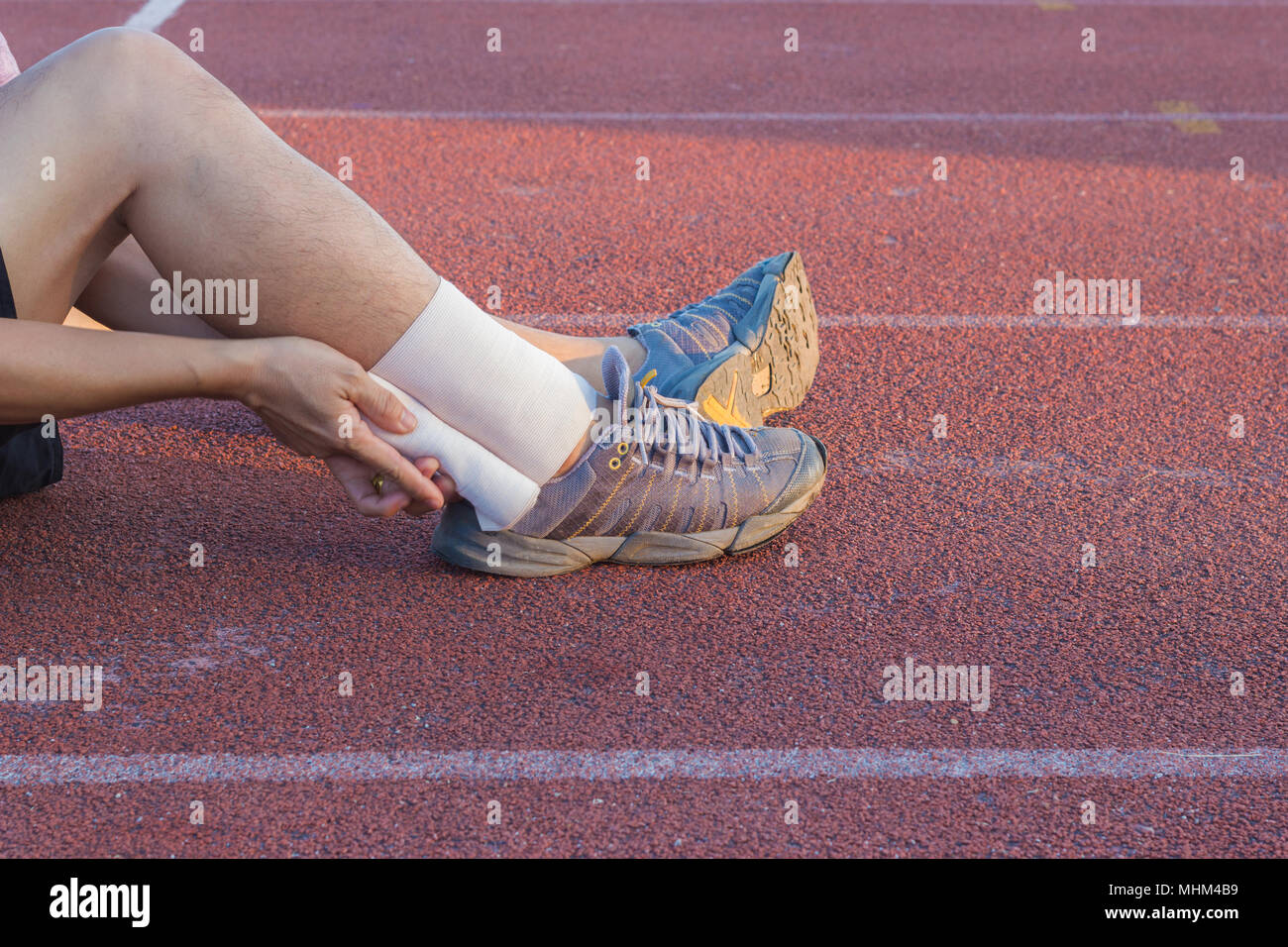 Male athlete applying compression bandage onto ankle injury of a