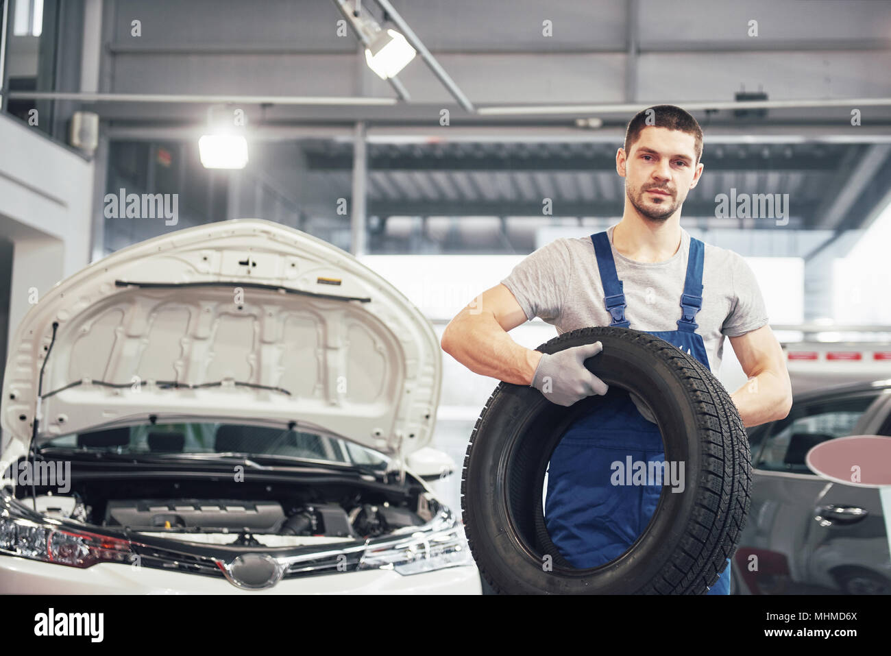 Mechanic holding a tire tire at the repair garage. replacement of winter and summer tires Stock Photo