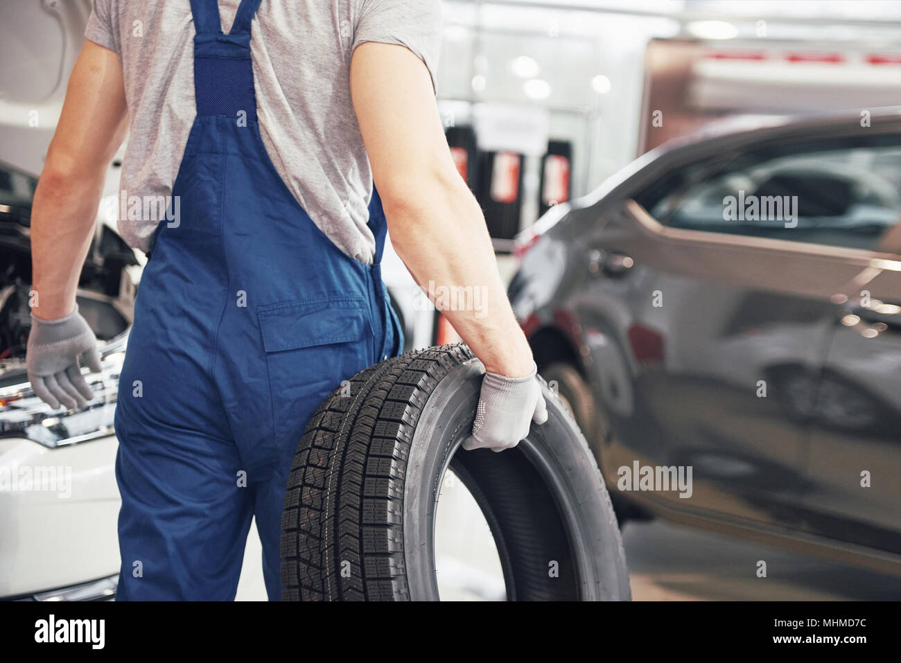 Mechanic holding a tire tire at the repair garage. replacement of winter and summer tires Stock Photo