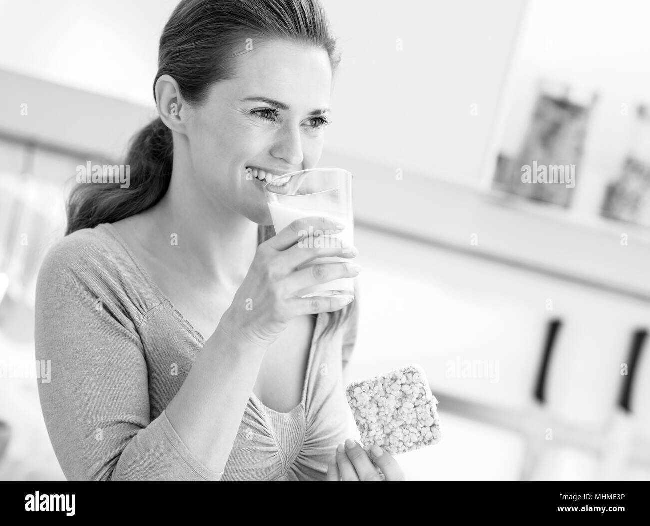 Young woman eating crisp bread with milk and looking on copy space Stock Photo