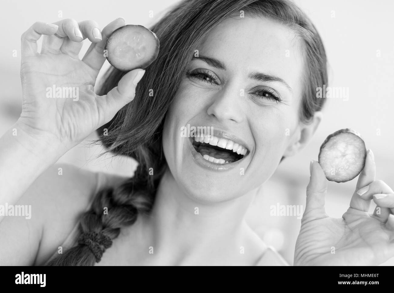 Smiling young woman showing slices of cucumber Stock Photo