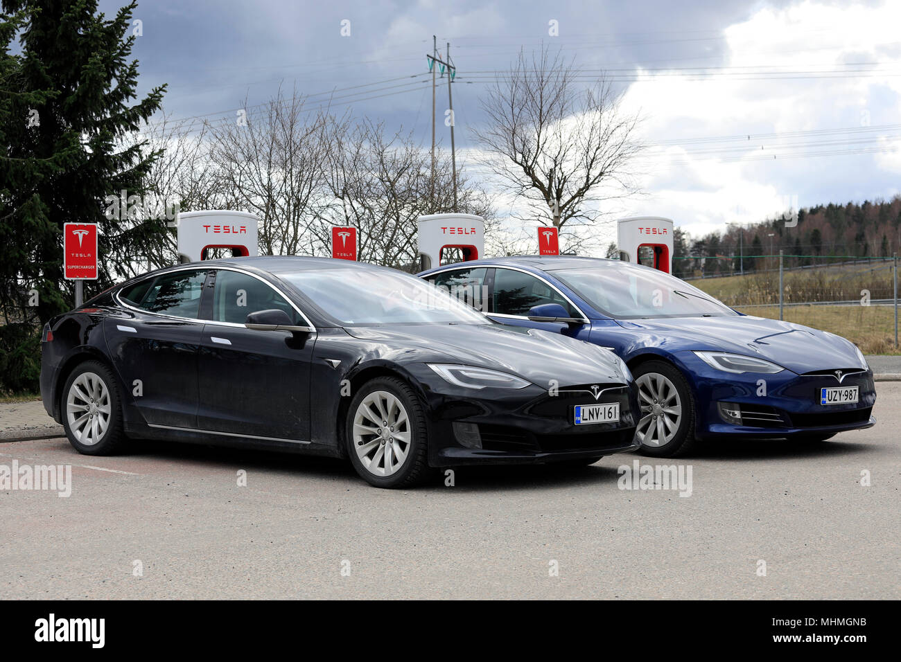 Two Tesla Model S electric cars of the updated or facelift exterior design are charging battery at Supercharger station on a day of spring in Paimio,  Stock Photo