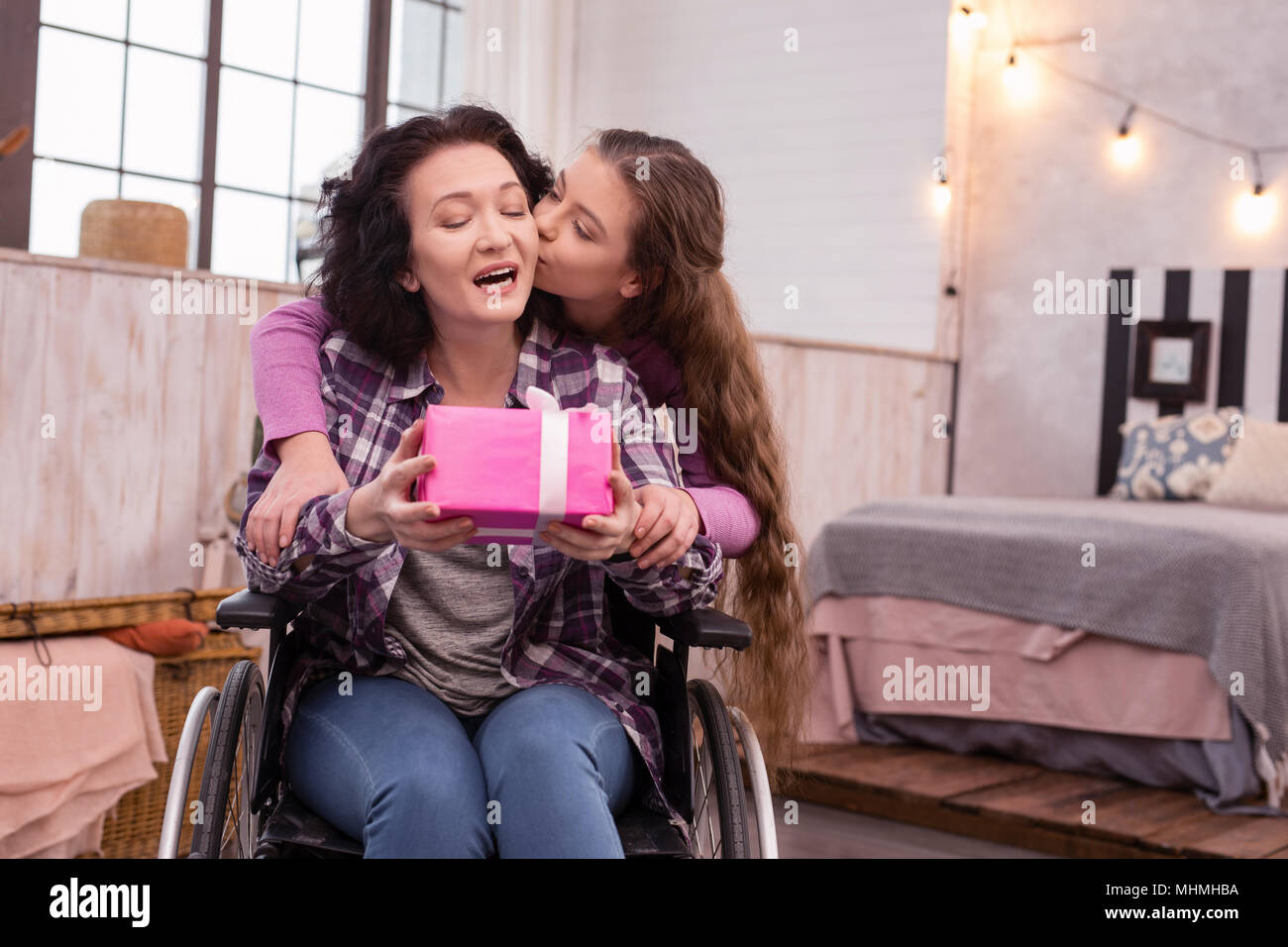 Loving girl giving surprise for amazed immobile woman Stock Photo