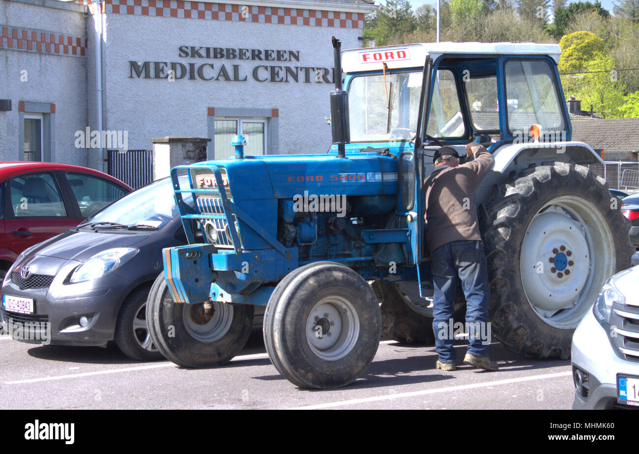 rural life, a farmer visits the doctors surgery driving his ford 5000 tractor, in skibbereen, county cork, ireland Stock Photo