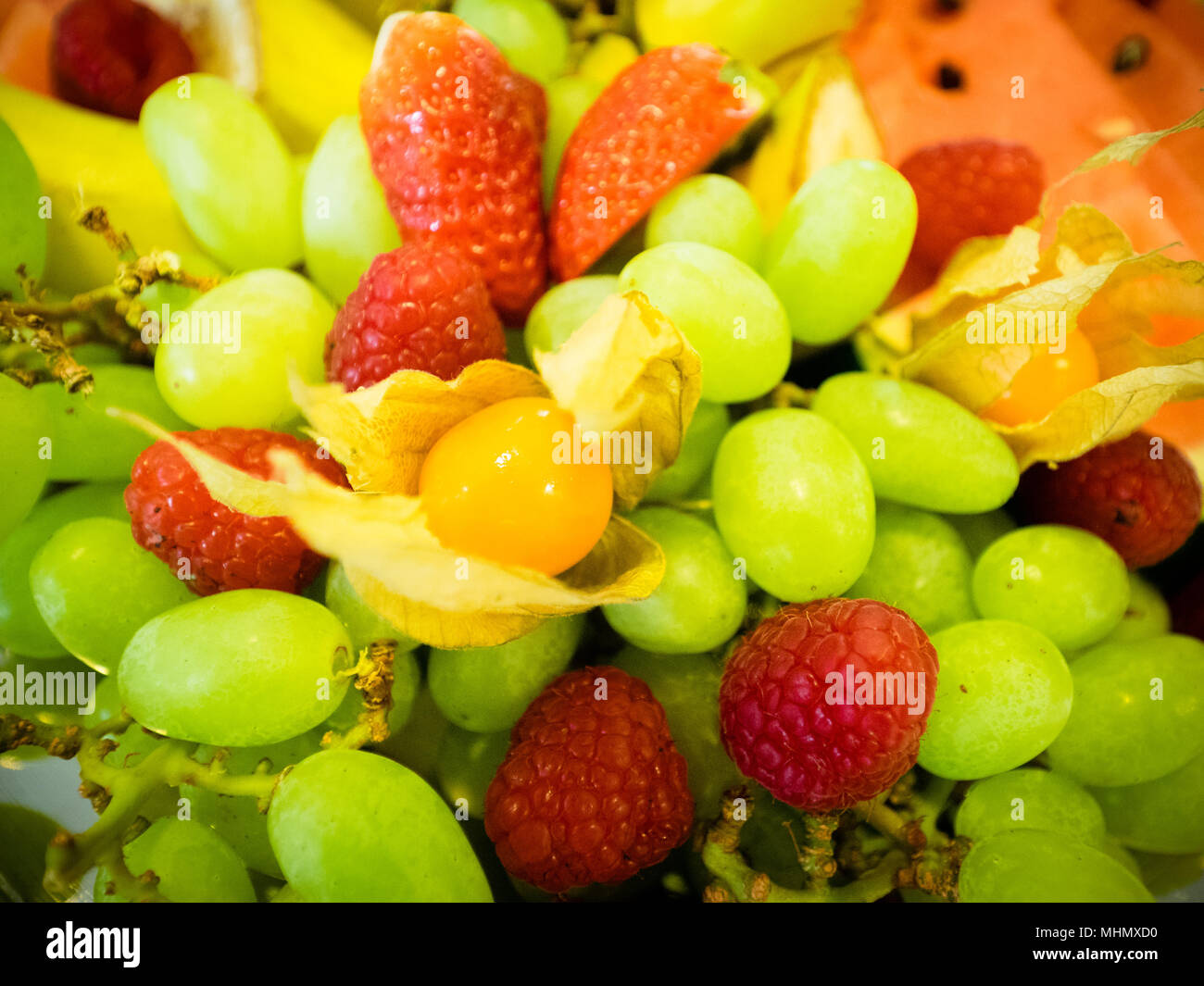 The colorful fruit plate with grapes, strawberries, physalis, mango and melon Stock Photo