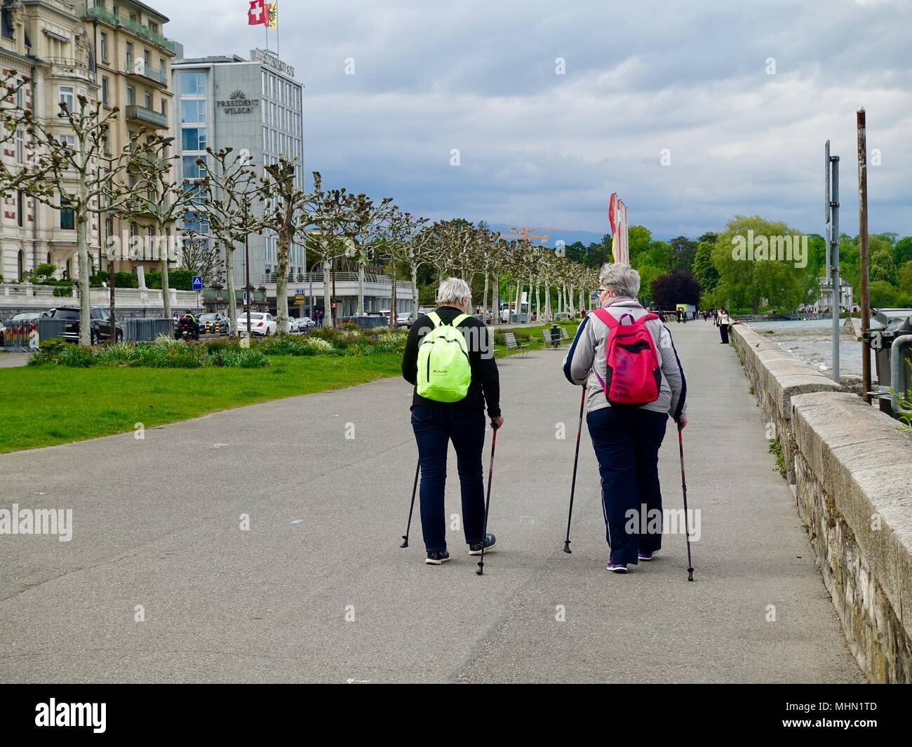 Two senior women walking for exercise, using walking sticks and wearing