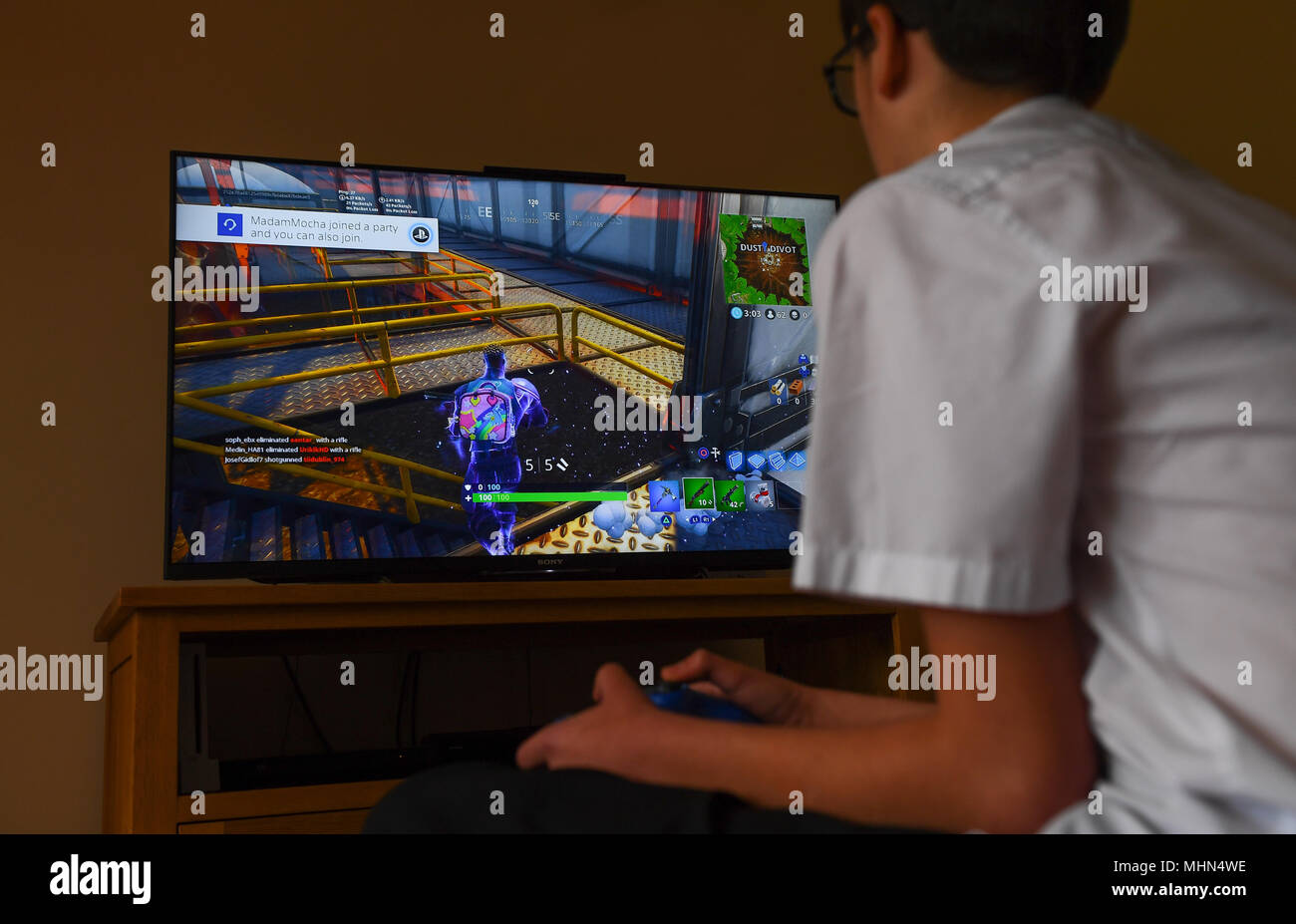 A teenager boy plays the hit computer game Fortnite on a large TV on a Playstation  4 console Stock Photo - Alamy