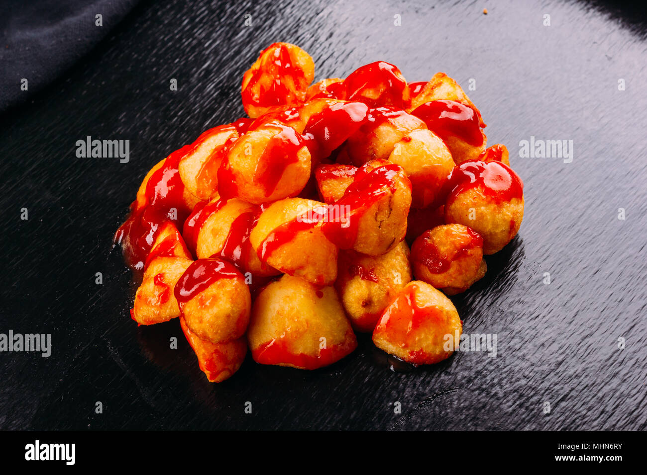 Typical spanish food, patatas bravas, fried potatoes with a hot sauce, on a dark background Stock Photo