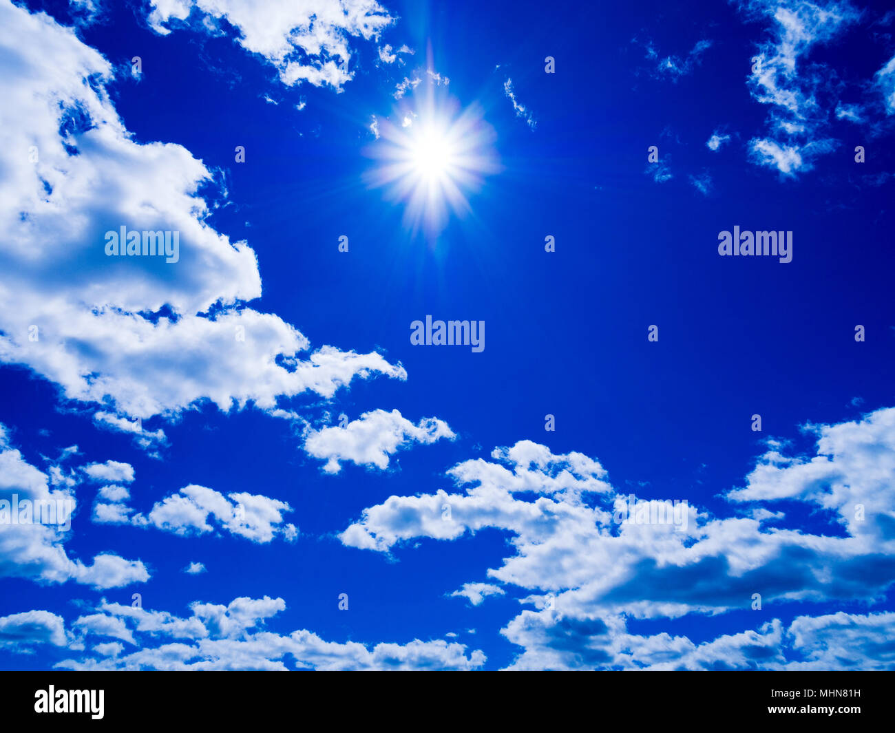 Blue sky with white fluffy clouds and sun Stock Photo - Alamy