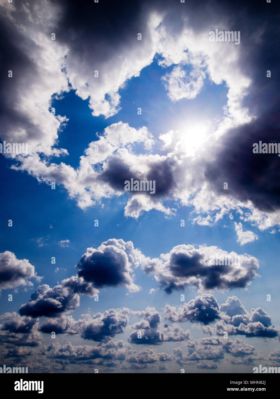 Blue sky with white fluffy clouds and sun Stock Photo - Alamy