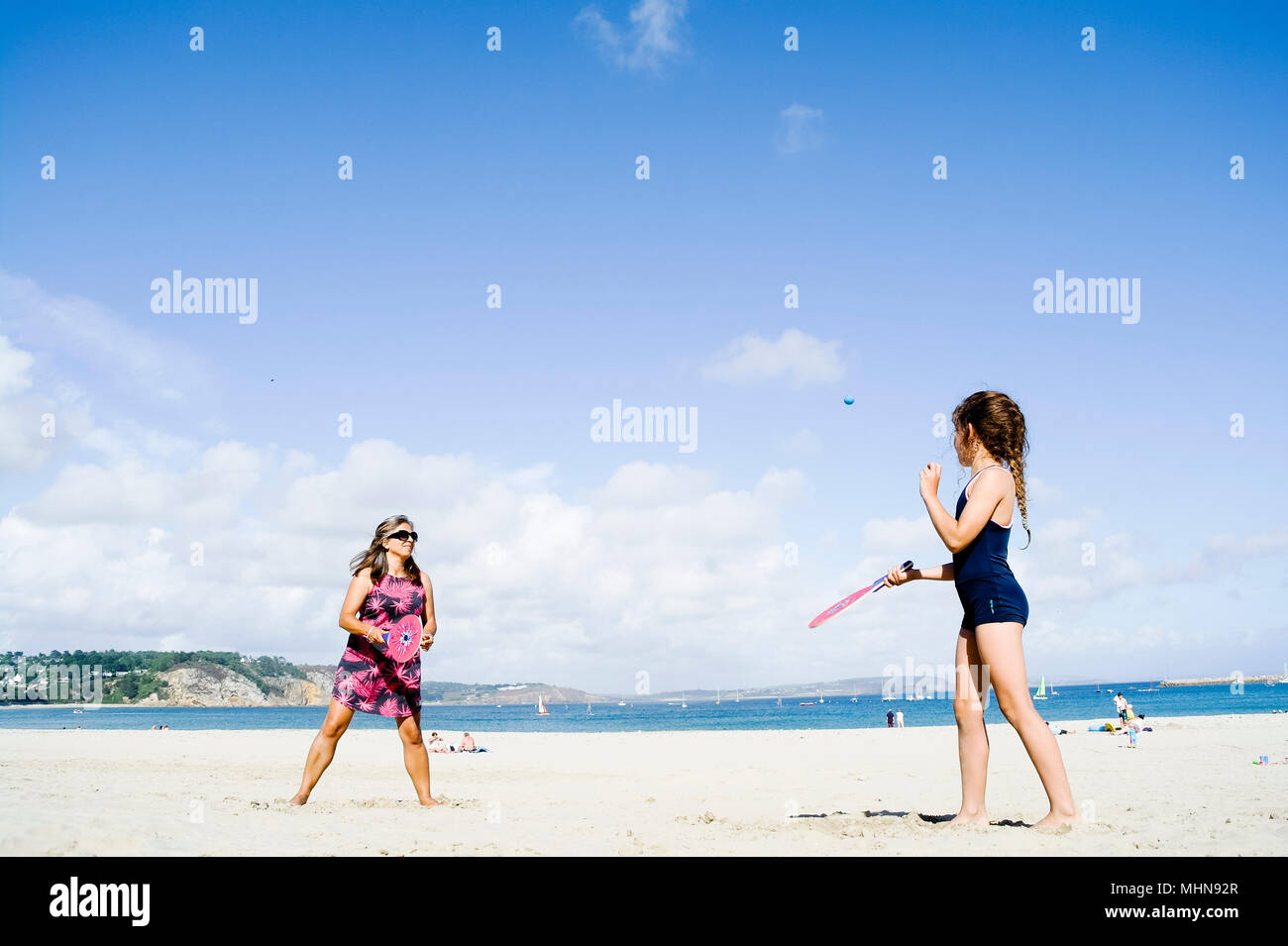 Mother and daughter playing beach bat and ball, Morgat, Brittany, France. Stock Photo