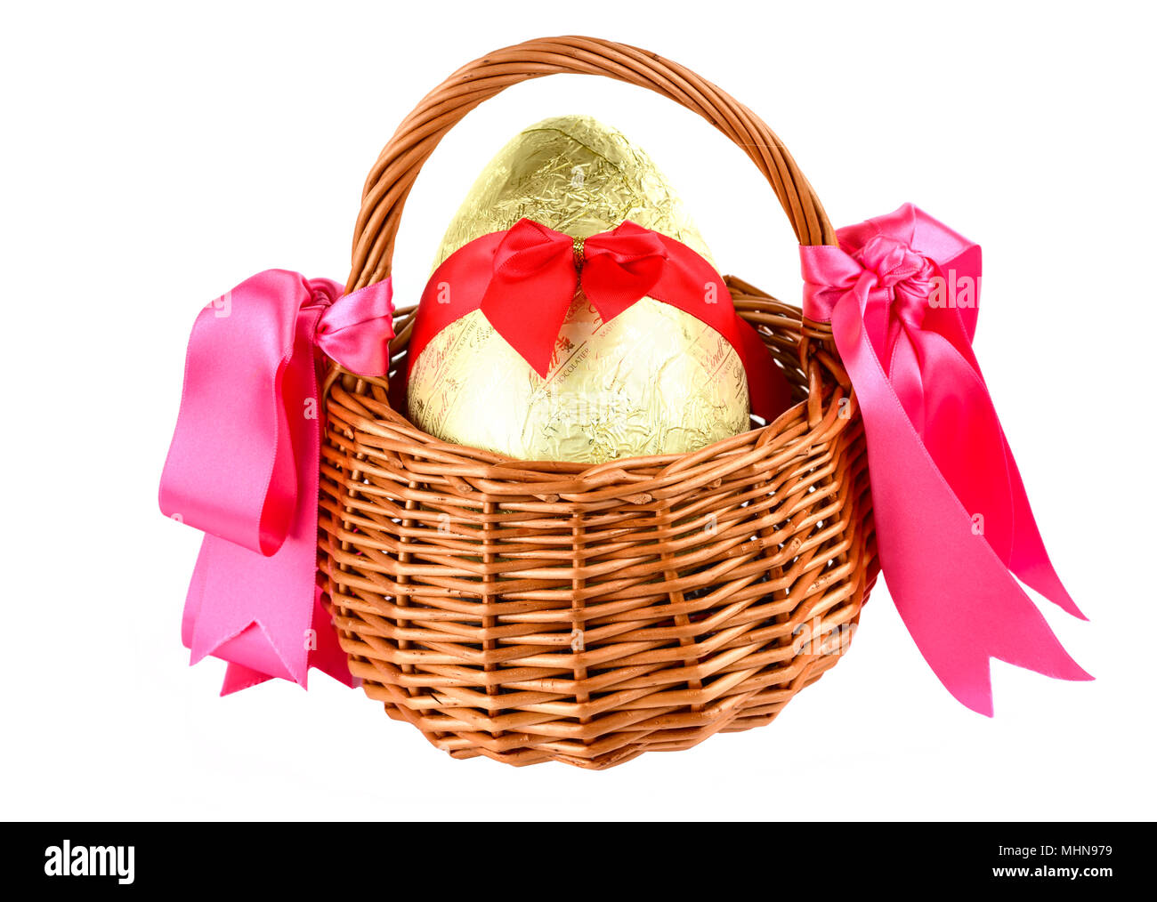 Wrapped chocolate easter egg with bow ina wicker basket Stock Photo