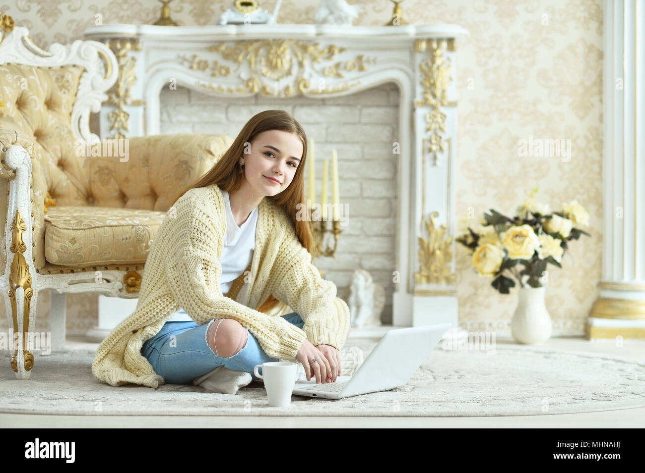 Beautiful teen girl sitting on floor and using laptop Stock Photo - Alamy