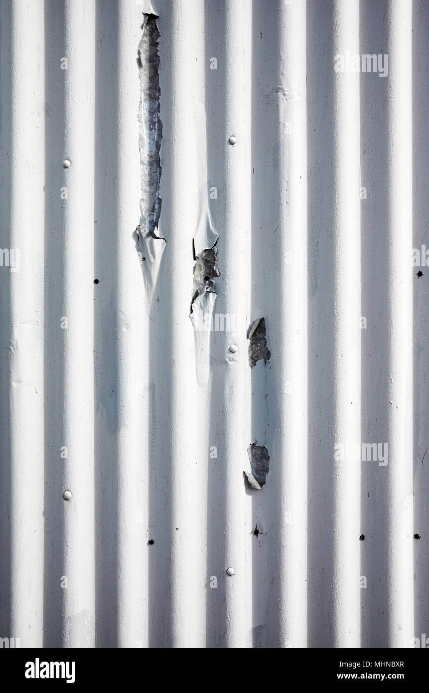 Weathered corrugated metal sheet with peeling paint, abstract