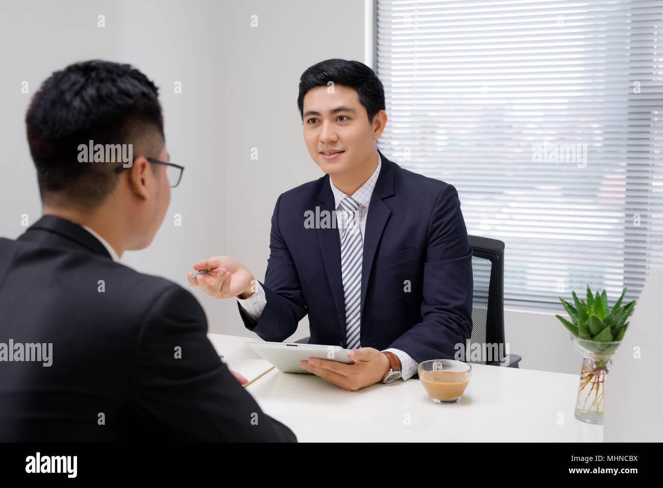Salesman explaining his idea of overcoming crisis to co-worker Stock Photo