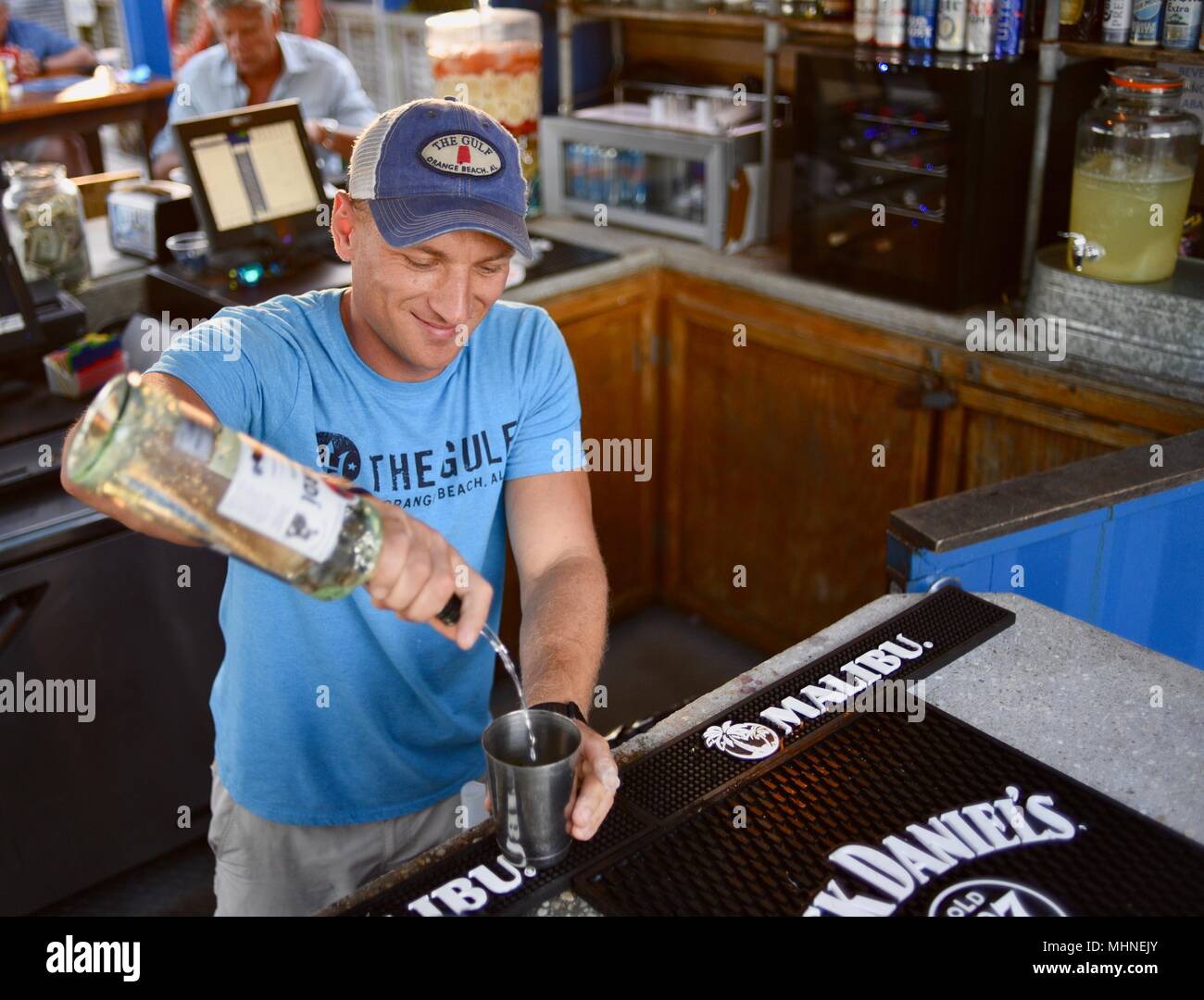 Handsome man pouring liquor drink cocktail at outside waterfront bar at