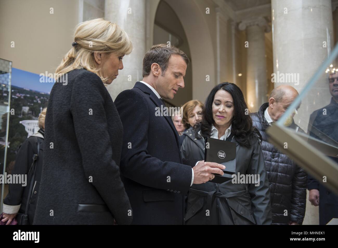 French President Emmanuel Macron (center) with his wife, Brigitte Macron (left), presents a gift to Karen Durham-Aguilera (right), executive director, Army National Military Cemeteries, in the Memorial Amphitheater Display Room at Arlington National Cemetery, Arlington, Virginia, April 24, 2018, April 24, 2018. President Macron's visit to Arlington National Cemetery was part of the first official State Visit from France since President Francois Hollande came to Washington in 2014. The French President along with his wife also visited the gravesite of former President John F. Kennedy. (U.S. Arm Stock Photo