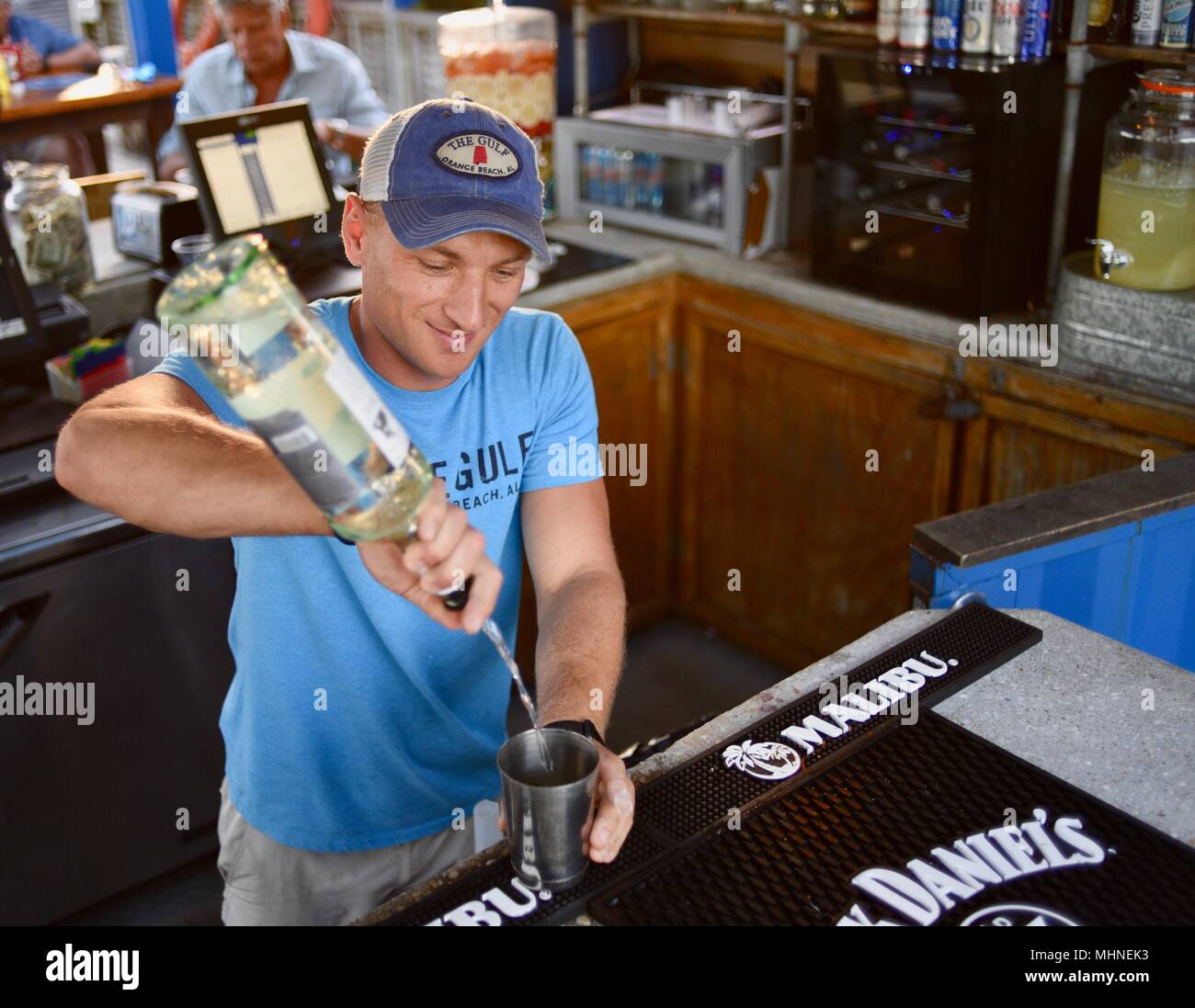 Handsome man pouring liquor drink cocktail at outside waterfront bar at