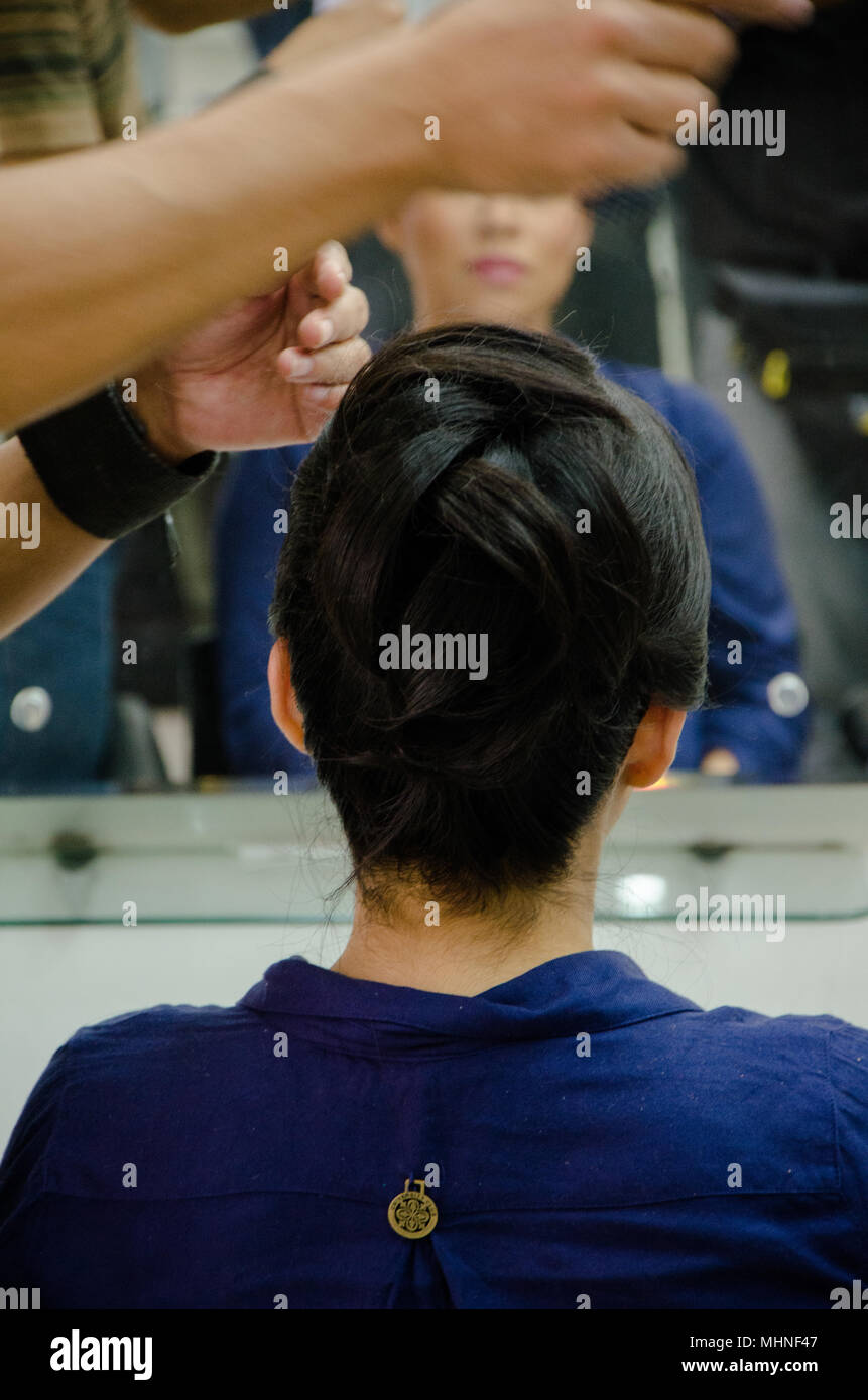 Stylist combing a woman in front of the mirror Stock Photo