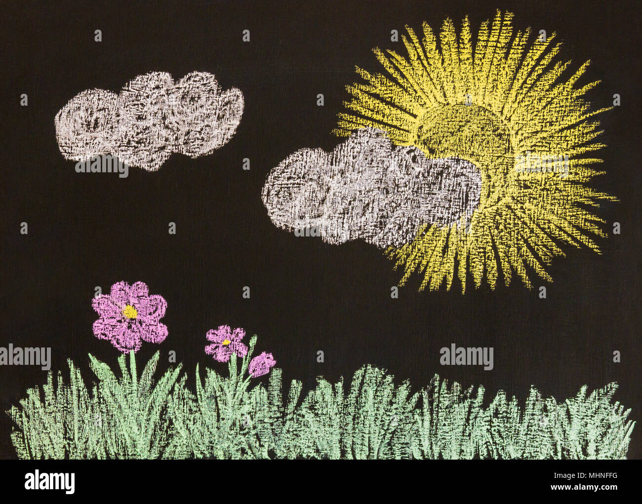 Chalk drawing of a landscape with grass, pink flowers, white clouds and sun on a blackboard drawing. Horizontal view. Stock Photo