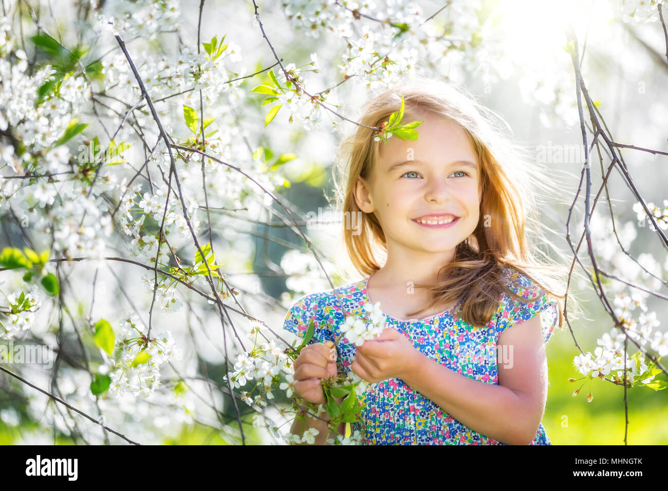 Happy little girl in cherry blossom garden Stock Photo - Alamy