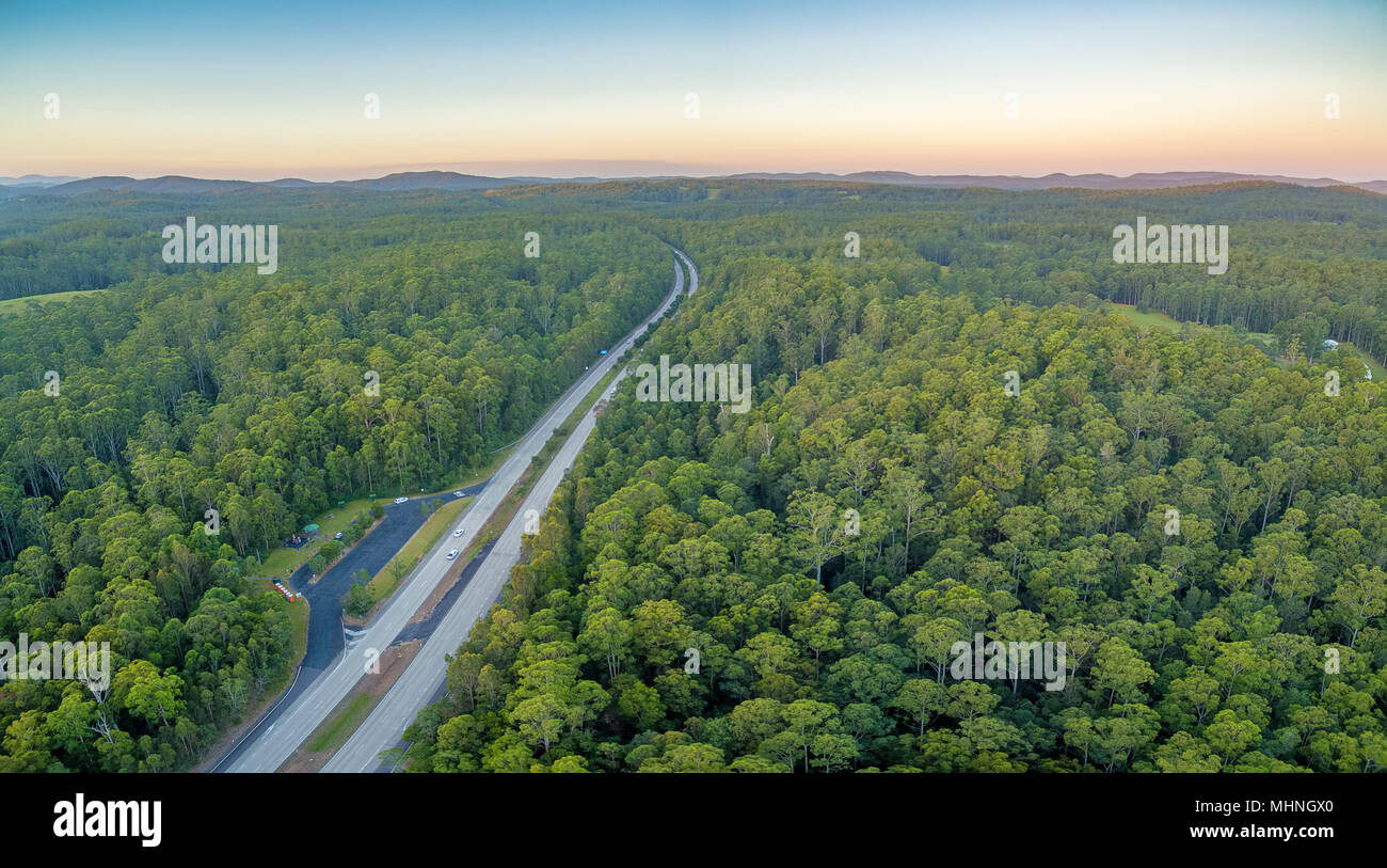 Highway passing through forest in rural area at sunset Stock Photo