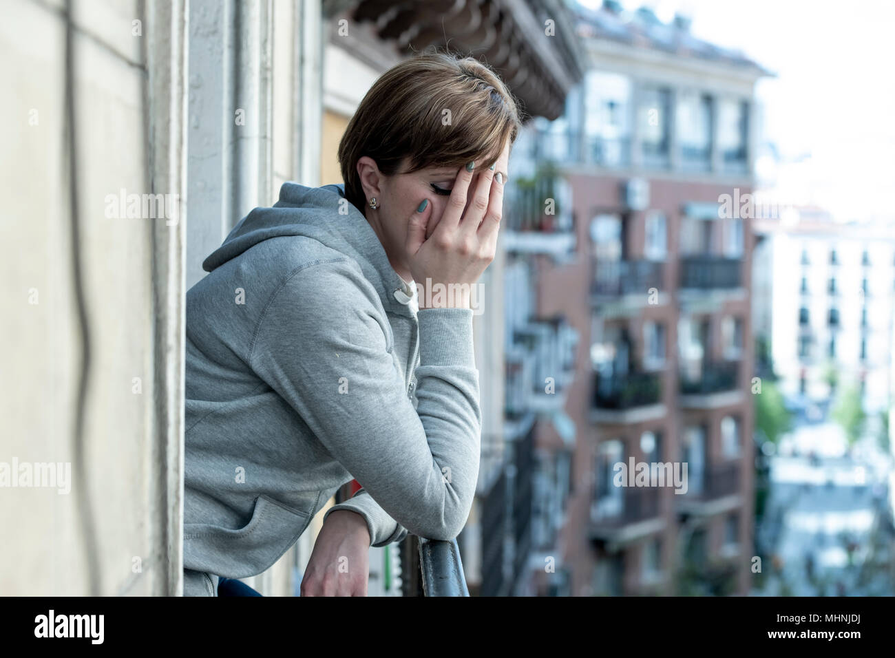Young attractive,red haired, unhappy lonely caucasian woman with depression looking sad on the balcony at home. feeling desperate and worthless in dep Stock Photo