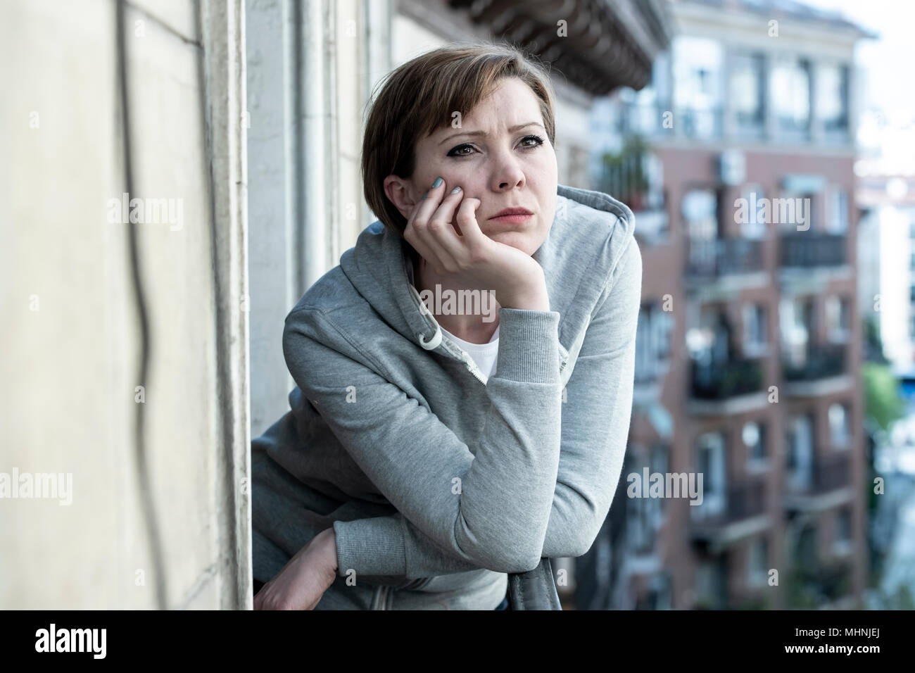 young beautiful, unhappy depressed lonely woman staring hopeless and worried on the balcony at home. having feelings of failure, dissatisfaction. Adul Stock Photo