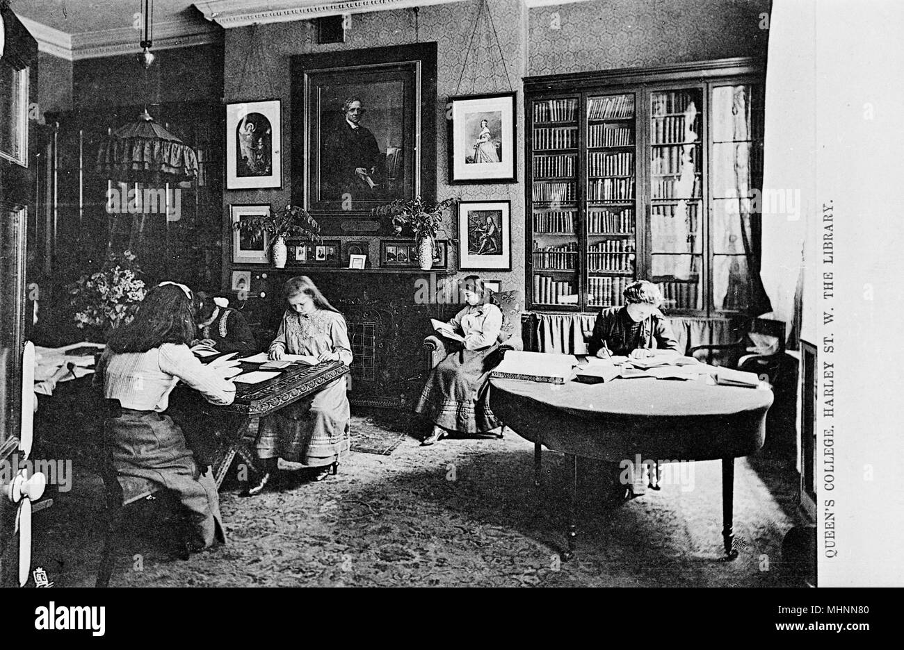 Young women reading and writing in the Library at Queen's College, a girls' independent school in Harley Street, London.     Date: circa 1905 Stock Photo