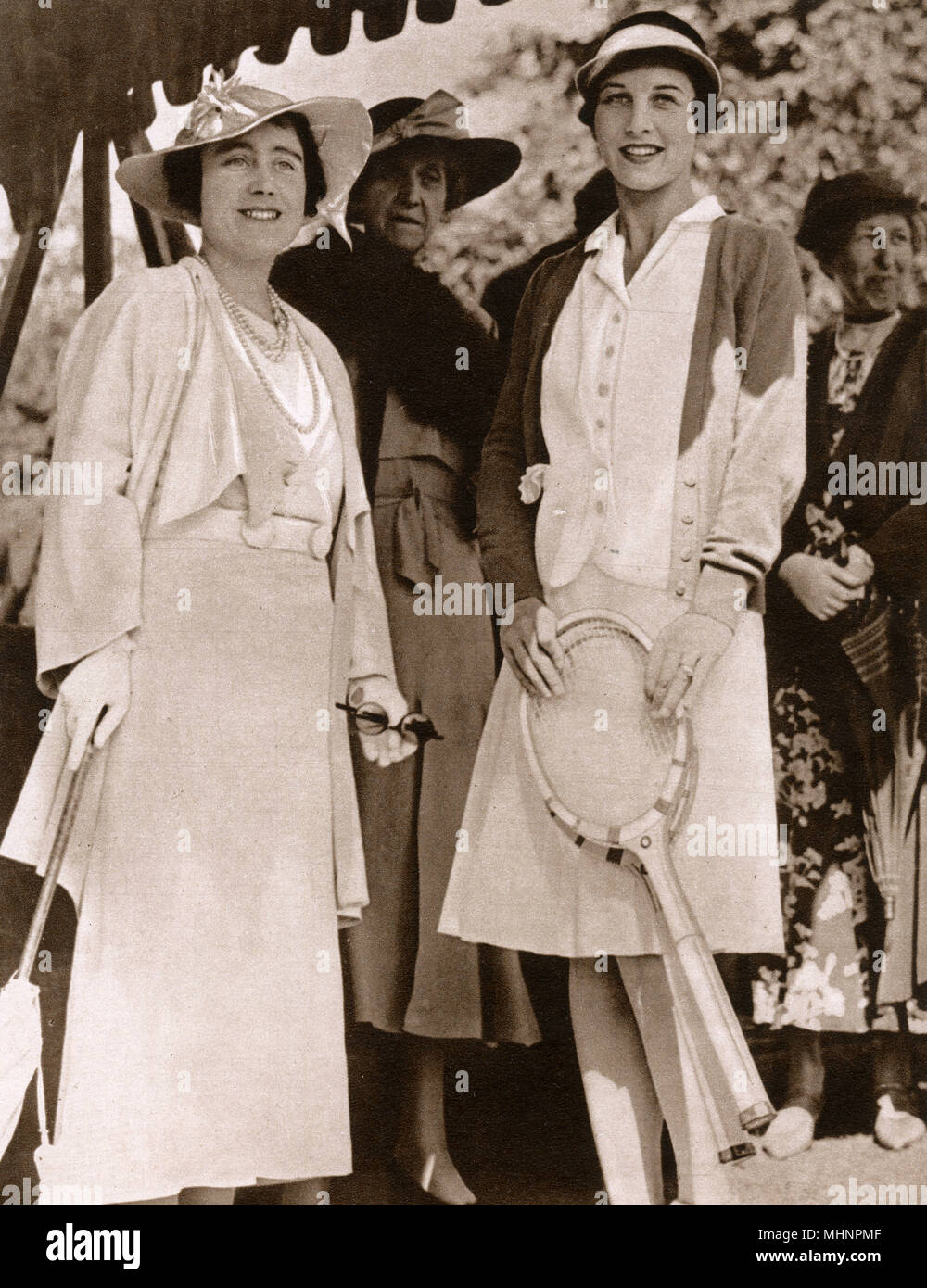 Elizabeth, Duchess of York (later Elizabeth, the Queen Mother 1900-2002) and Helen Wills Moody (1905-1998) at the Lawn Tennis Championships at Wimbledon. Princess Marie Louise of Schleswig-Holstein (1872-1956) stands behind the     Date: 1935 Stock Photo