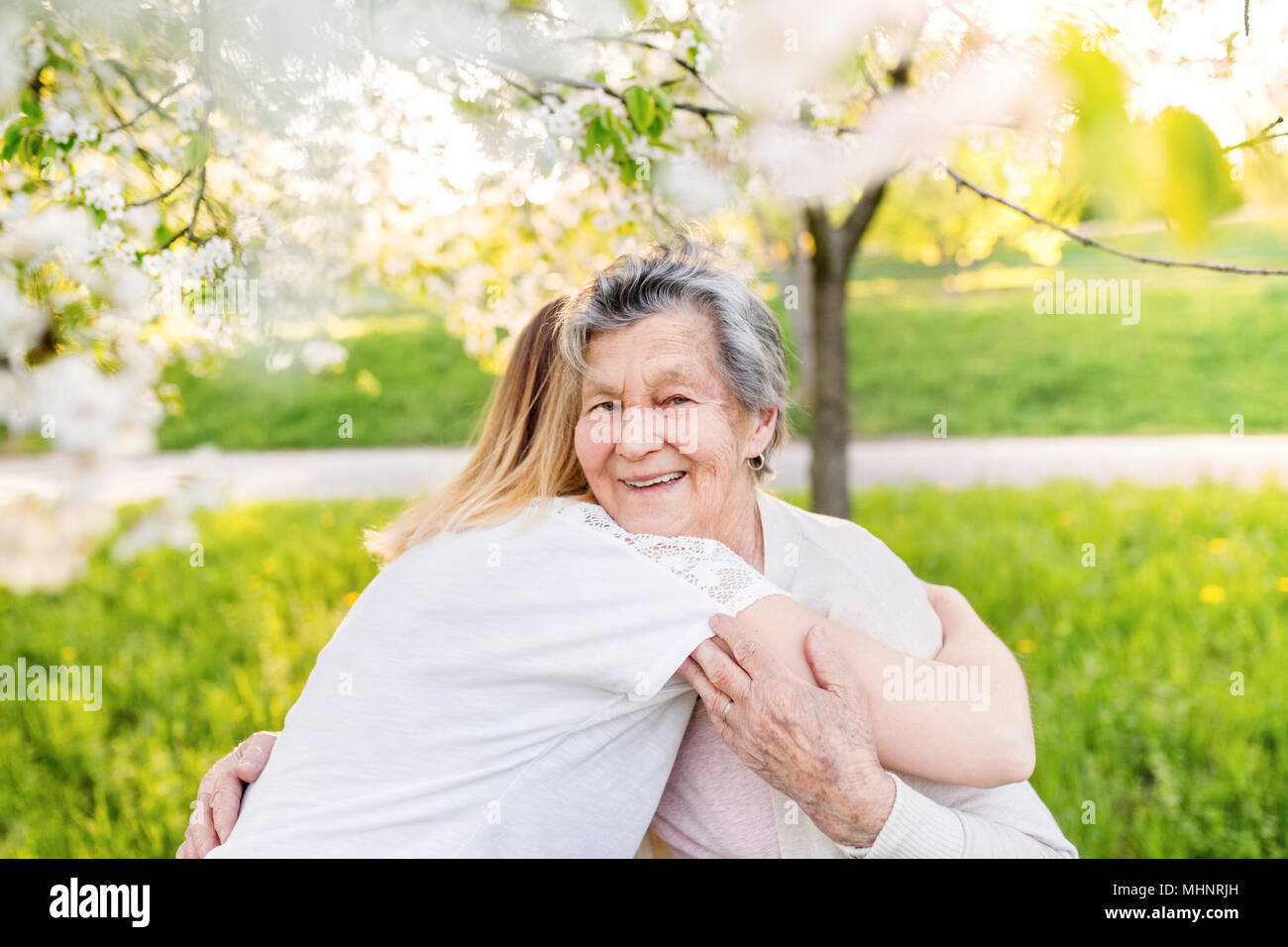 Elderly grandmother and granddaughter hugging in spring nature. Stock Photo