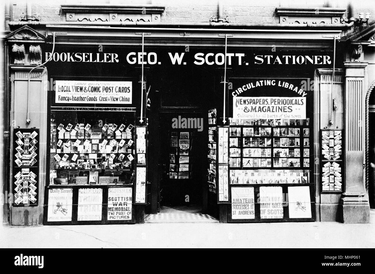 Premises of Geo W Scott, Bookseller and Stationer, somewhere in Scotland, with newspaper headlines on display outside, postcards in the left window and circulating library books in the right window.      Date: circa 1930s Stock Photo