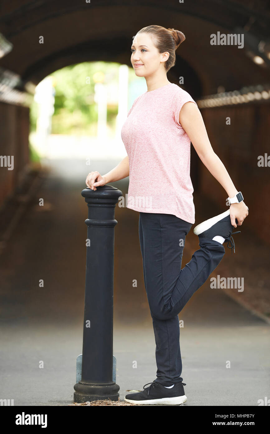 Young Woman Stretching Whilst Exercising In Urban Environment Stock Photo