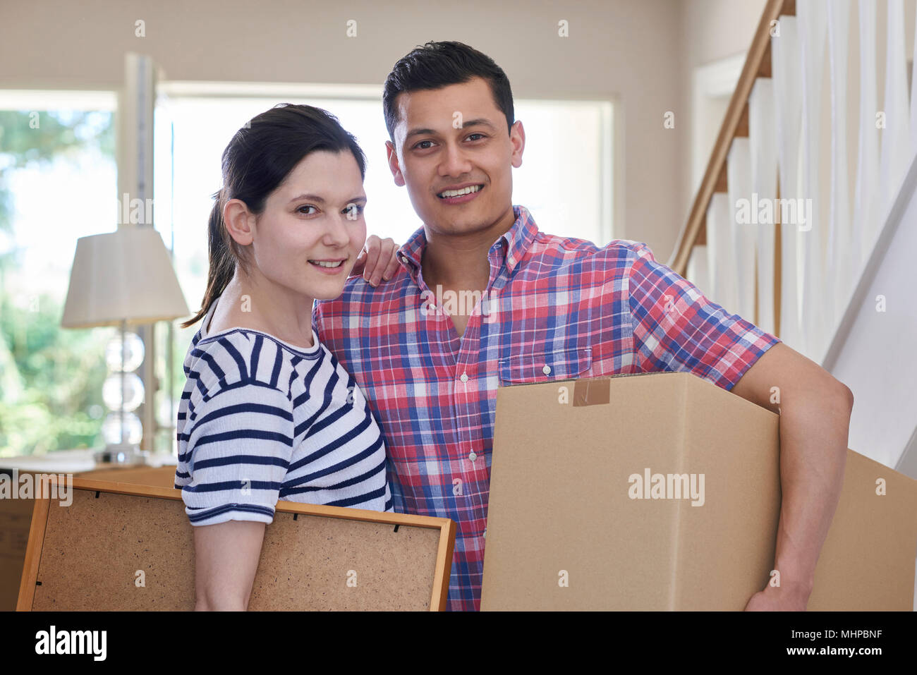 Portrait Of Couple Carrying Boxes Into New Home On Moving Day Stock ...
