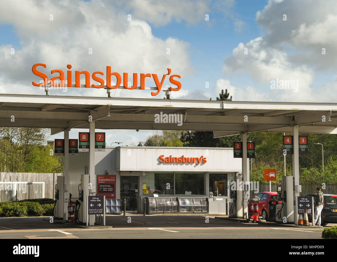 Wide angle view of the large sign above a petrol station at a Sainsbury's supermarket and the kiosk Stock Photo
