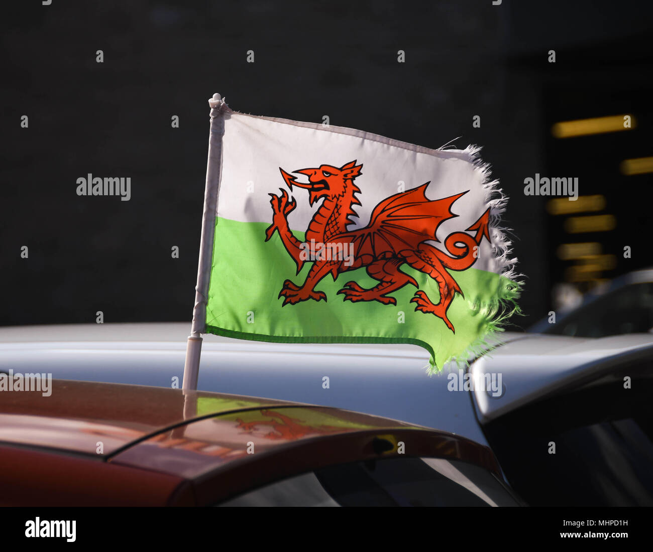 Small Welsh Rad Dragon flag with frayed edges flying from a car Stock Photo