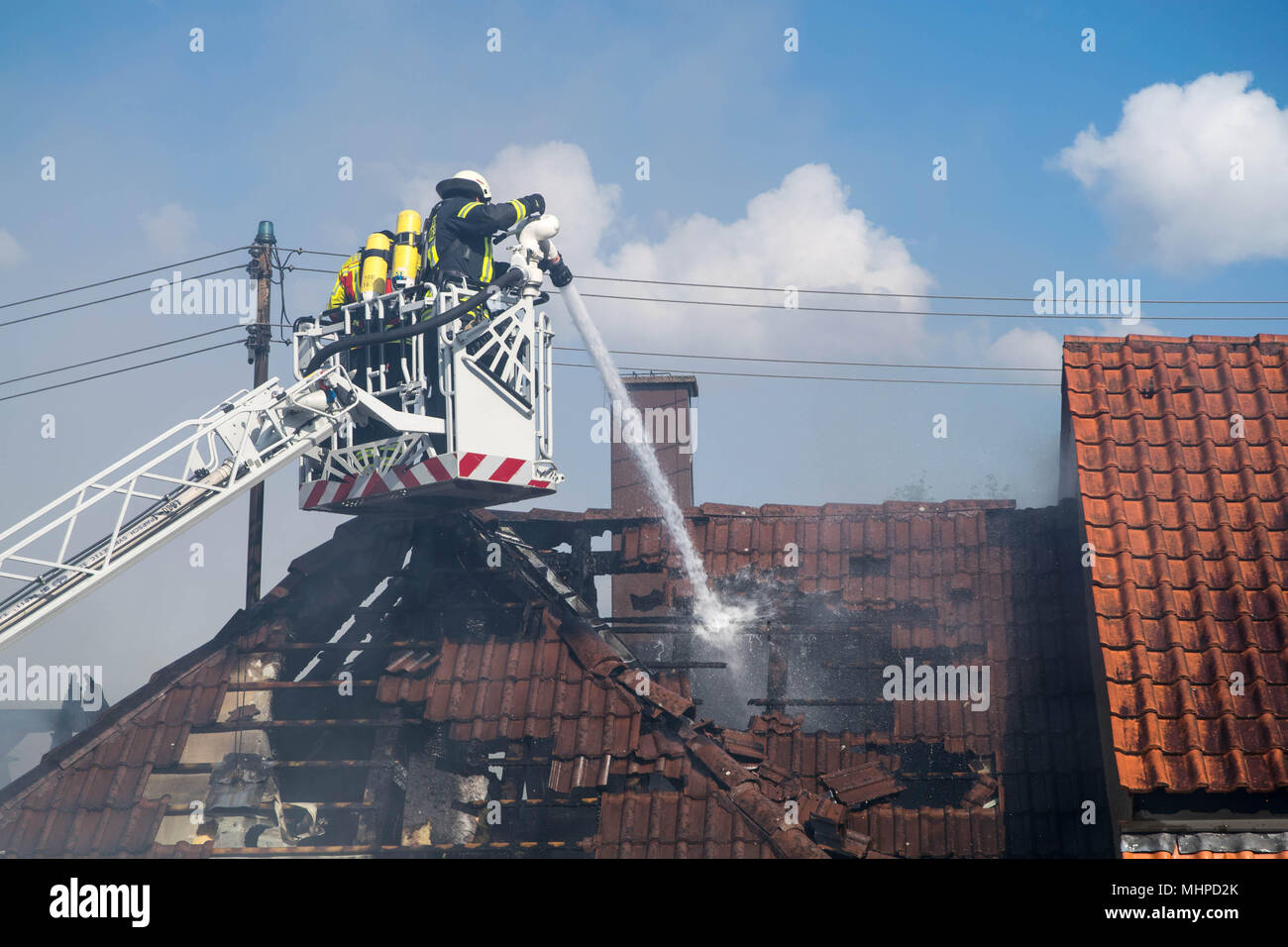 two Fireman with equipment on the Drehleiter ( aerial ladder ) extinguishing fire Stock Photo