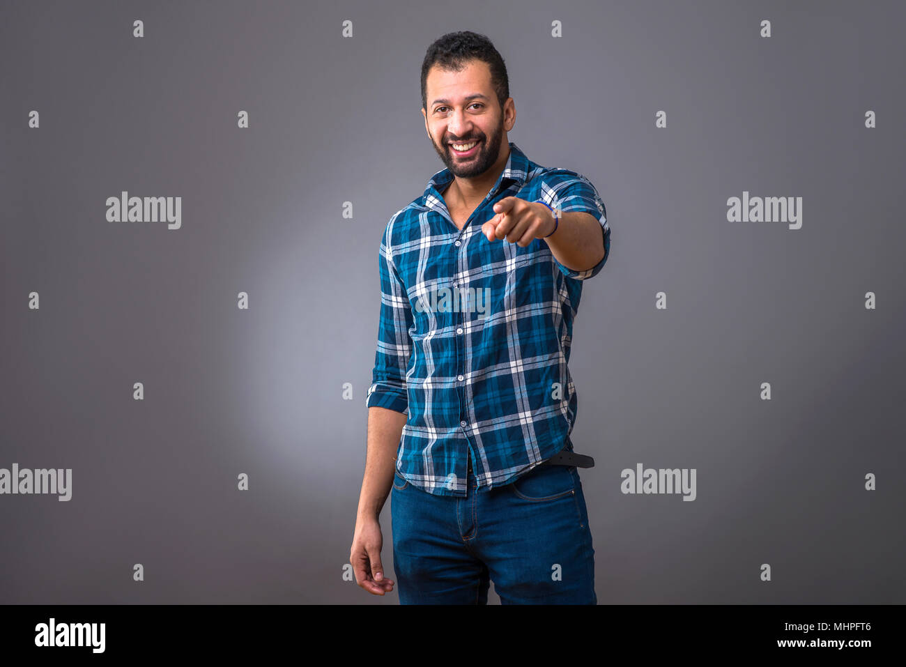 A young black man standing and smiling while pointing in to the camera Stock Photo